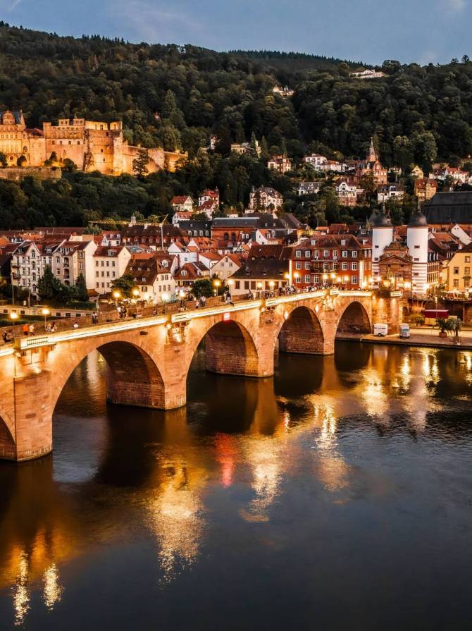 A stunning view of Heidelberg Castle and the Old Bridge over the Neckar River in Heidelberg, Germany during twilight.